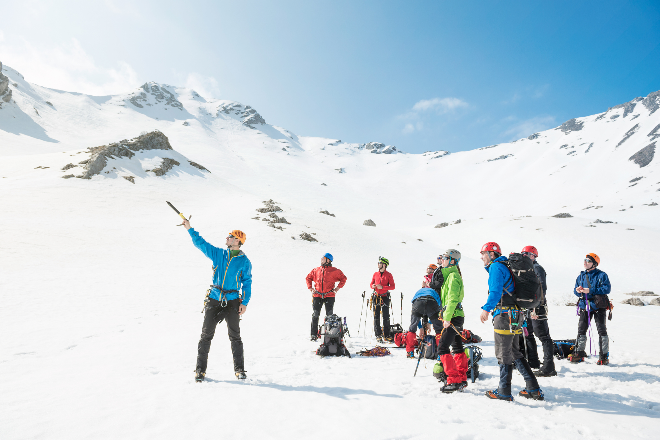 Group of mountaineers preparing to climb up to the mountain peak. Their leader showing them the way.