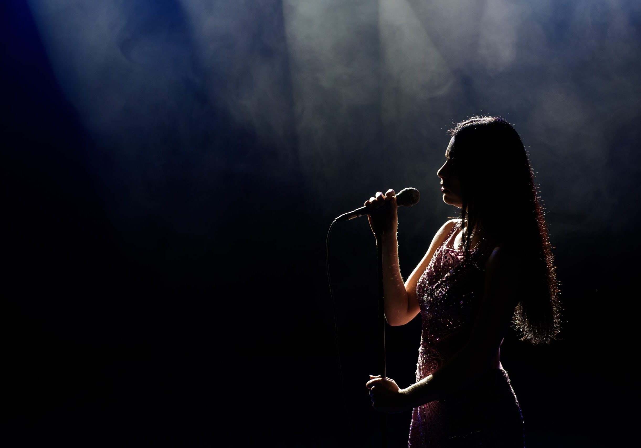 Portrait of beautiful singing woman on dark background